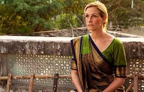 Scene of Elizabeth sitting on a balcony, dressed in a traditional sari, serenely contemplating the place where she is.